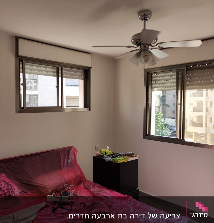 חדר עם מיטה מכוסה בניילון אדום, צבעים על שידה